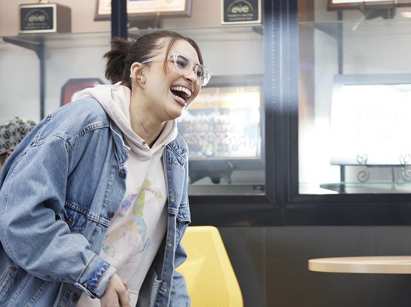 Female student holding ping pong paddle laughs.