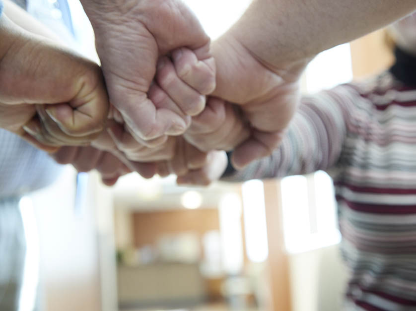 Multiple fists come together at the moment they create a celebratory fist bump.