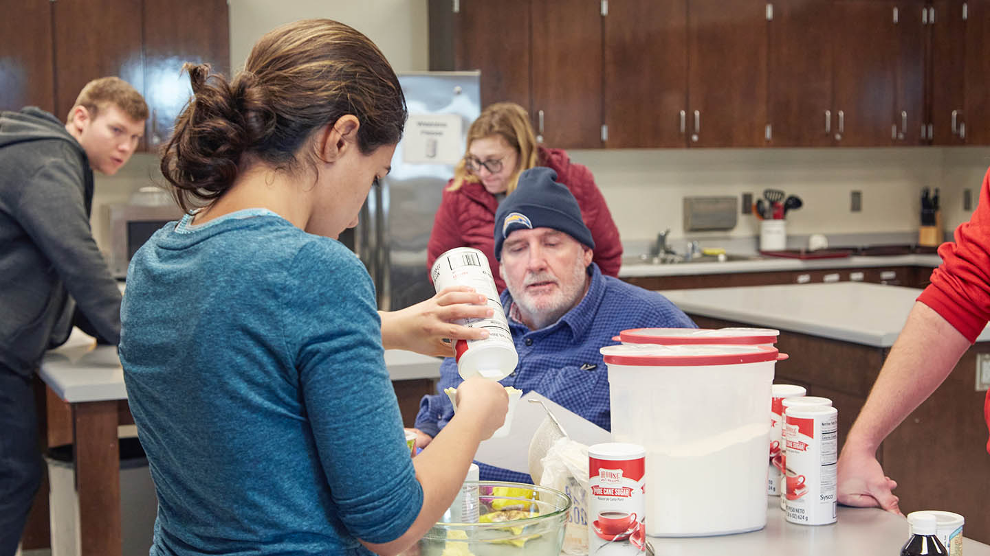 Students get counsel from a direct support coordinator on the importance of measuring ingredients in their recipes.