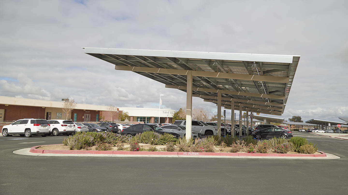 Cars throughout parking lot are shaded by long rectangular sun shades topped with solar panels.