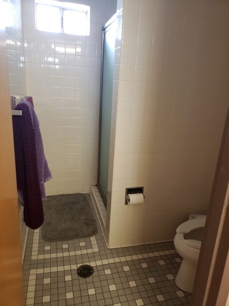 A single, enclosed bathroom featuring a toilet and shower.
