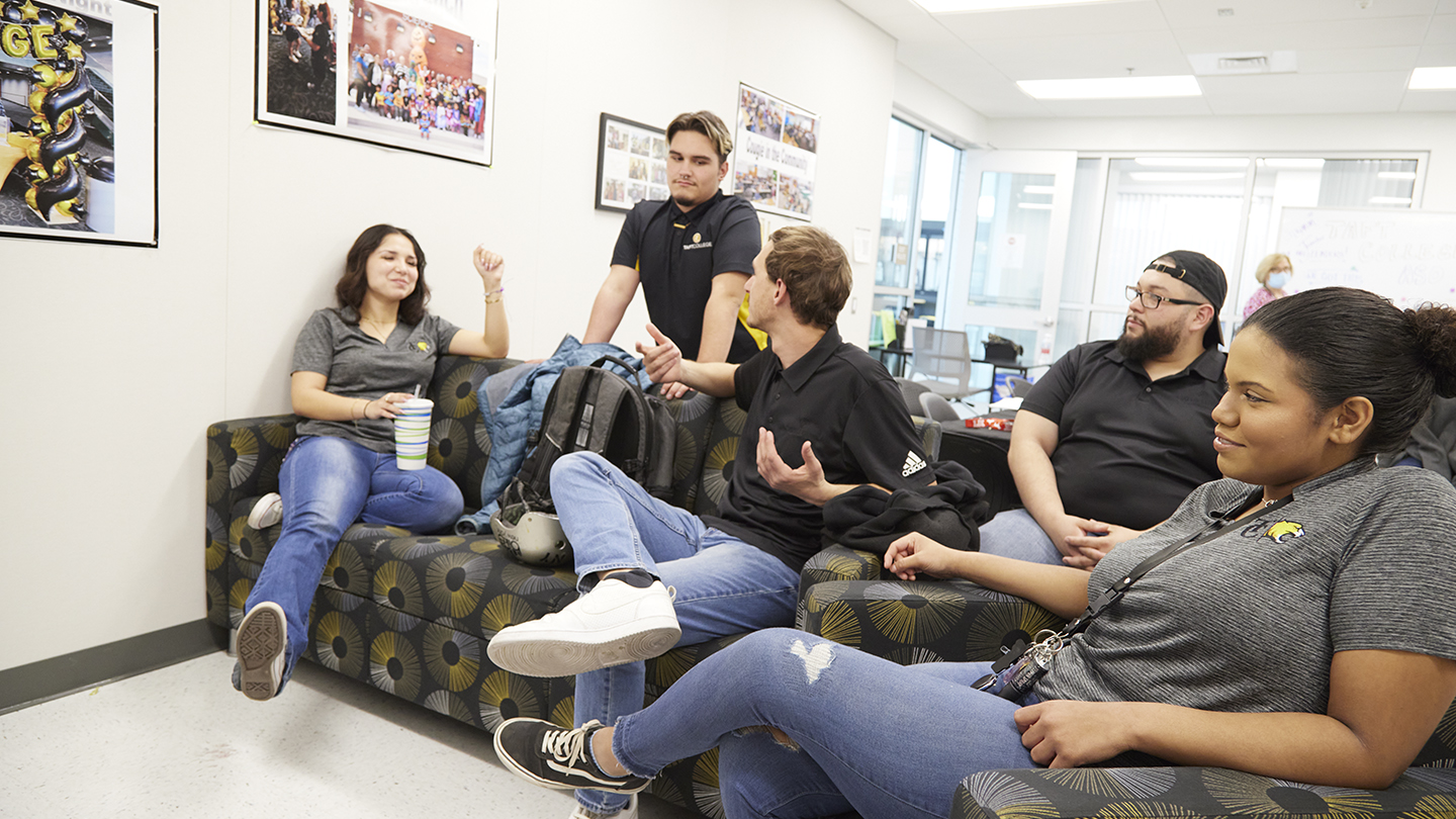 Five students lounge on couch and armchair.