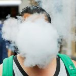 A photo of an individual whose face is obscured by a cloud of vapor